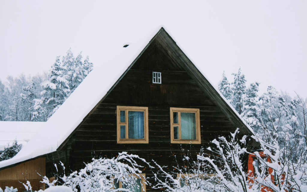A wooden house covered in fresh snow.