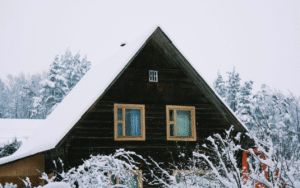 A wooden house covered in fresh snow.